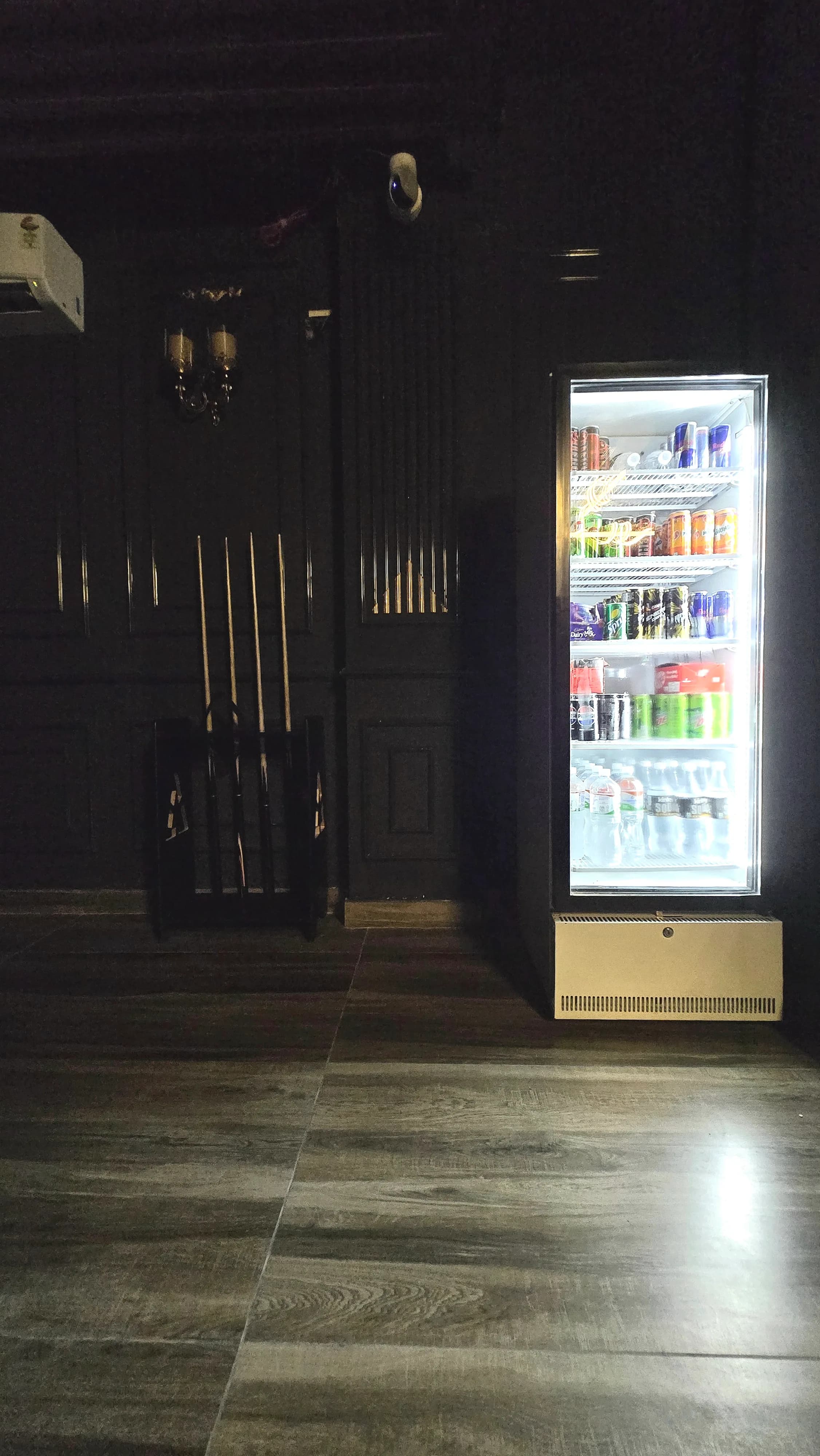 Cue rack beside a lit drinks fridge